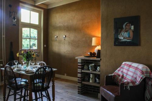 a room with a table with chairs and a picture of a woman at Farmhouse De Hoeve B&B apartment in Tonden