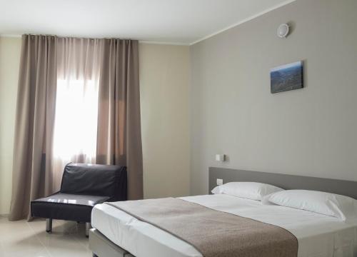 a bedroom with a bed and a chair and a window at Hotel & Wellness Stella Delle Langhe in Govone