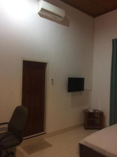 a bedroom with a bed and a chair and a television at Wisma Maharani in Wanci