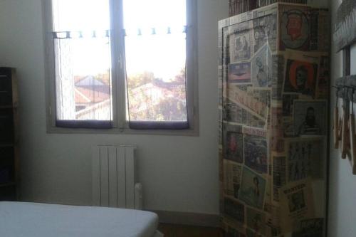 アルヴェールにあるMon p'tit nidのベッドルーム(ベッド1台、窓付)と新聞が備わります。