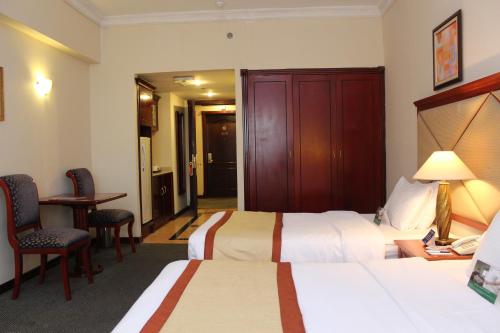 a hotel room with two beds and a table and chairs at Al Diar Mina Hotel in Abu Dhabi