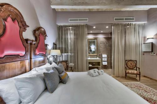 a bedroom with a large white bed with a wooden headboard at Palazzo Consiglia - IK Collection in Valletta