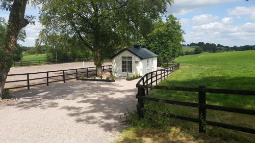 a small white house in a field next to a fence at The Stable Lodge Cannaway House in Macroom