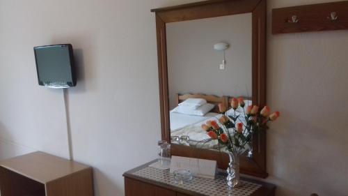 a bedroom with a mirror and a vase of flowers on a table at Olympus View Rooms Sauna & Spa in Litochoro