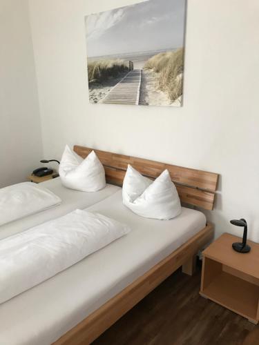 twee bedden met witte kussens en een foto aan de muur bij Hotel Rheinischer Hof in Geldern