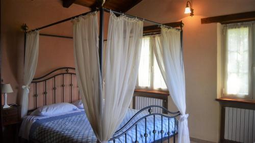 a bedroom with a canopy bed with white curtains at Agriturismo il Roccolo in Pantasina