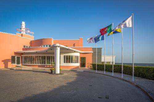 a building with flags in front of the ocean at Luna Hotel Turismo in Abrantes