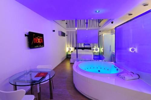 ein Bad mit einer Badewanne, einem Tisch und einem Bett in der Unterkunft Nexos Motel Piedade - Adults Only in Recife