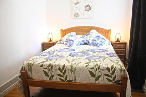 a bed with a blue and white comforter and two night stands at Casa Azul Altamira in Viana do Castelo
