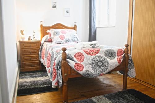 ein Schlafzimmer mit einem Bett mit einer Decke und einer Kommode in der Unterkunft Casa Azul d'Altamira in Viana do Castelo