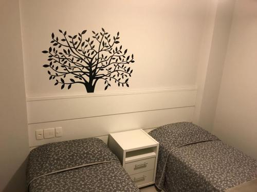 1 dormitorio con 2 camas y un árbol en la pared en Edifício Dalpiaz, en Balneário Camboriú