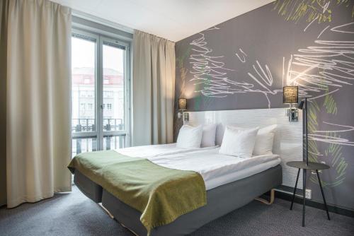 ein Schlafzimmer mit einem Bett und einer Wand mit einem Gemälde in der Unterkunft Quality Hotel Park Södertälje City in Södertälje