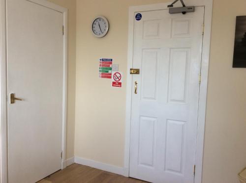 a white door with a clock on a wall at Rudan Guest House AB53 6UQ in New Deer
