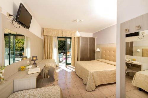 Habitación de hotel con cama y sala de estar. en Hotel Dei Tigli, en Lido di Camaiore
