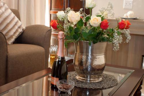 a table with two bottles of wine and a vase of roses at Keret Accommodation in Bellville
