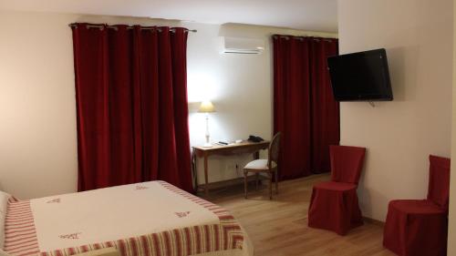 een hotelkamer met rode gordijnen, een bed en een bureau bij Castellu in Lucciana