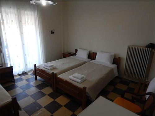 sypialnia z 2 łóżkami i podłogą wyłożoną szachownicą w obiekcie Lito Hotel w mieście Prinos