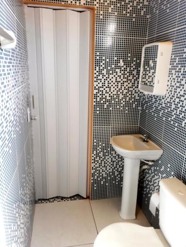 a bathroom with a white sink and a toilet at Suítes Canaã in Canoa Quebrada