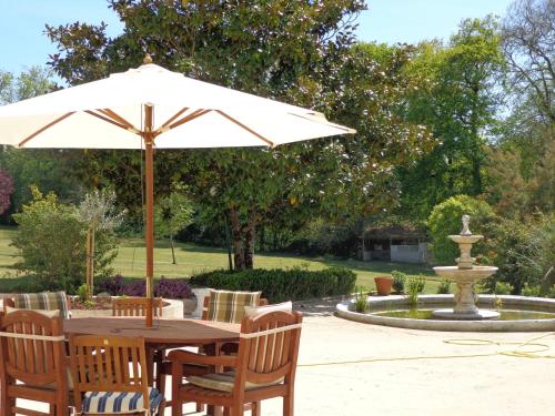 a table with an umbrella next to a fountain at La Maison Ribotteau in LʼIsle-Jourdain