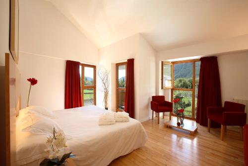 a bedroom with a large white bed with red curtains at Tierra de Biescas in Biescas