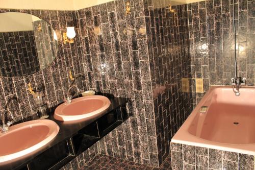 a bathroom with two sinks and a tub and a mirror at Le France in Loudéac