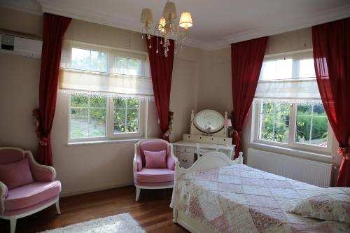1 Schlafzimmer mit einem Bett und 2 rosa Stühlen in der Unterkunft Damla Pansiyon in Sapanca