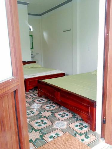 two beds in a room with a tile floor at Homestay Moc Chau in Mộc Châu