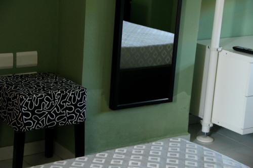 a mirror and a stool in a green room at Hotel Sauro in Viareggio