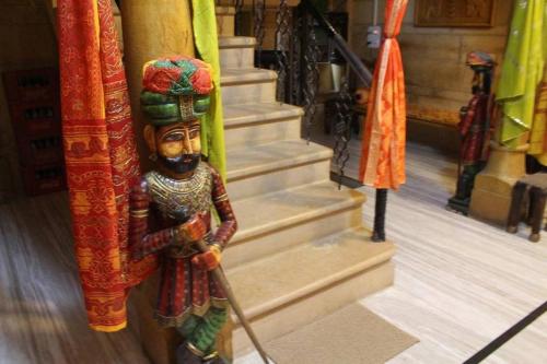 a statue of a man with a broom in front of stairs at Tripli Hotels Prithvi Palace in Jaisalmer