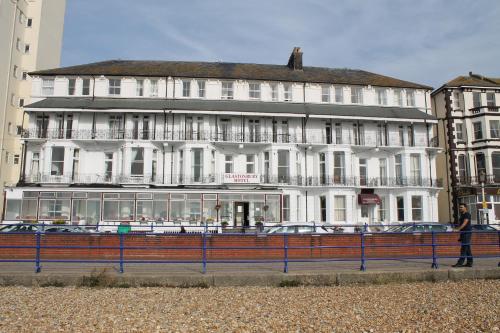 a large white building with cars parked in front of it at Glastonbury Hotel in Eastbourne