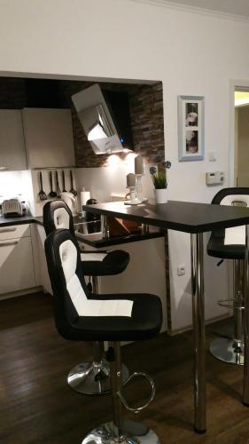 a kitchen with black and white chairs and a table at FeWo Wilhelmshaven Voslapp 267 in Wilhelmshaven