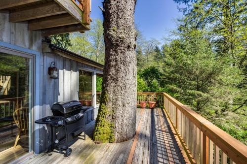 a grill on a deck next to a tree at Cascade Head Salmon River Getaway in Three Rocks