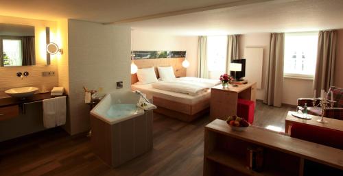 um quarto com uma cama, uma banheira e um lavatório em schlossmühle - lean luxury boutique hotel em Glottertal