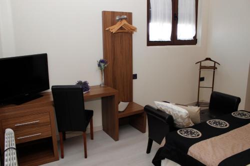 a room with a bedroom with a desk and a television at Palacete Maria Rosa in Baños de la Encina