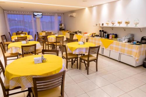 a dining room with yellow tables and chairs at Hotel Nova Aliança in Chapadão do Sul