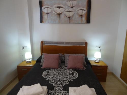 a bedroom with a bed with two night stands and two lamps at Costa Marina III Oropesa Apartment in Oropesa del Mar