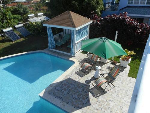 a pool with a gazebo and a green umbrella at Royal Vista Villa in Duncans