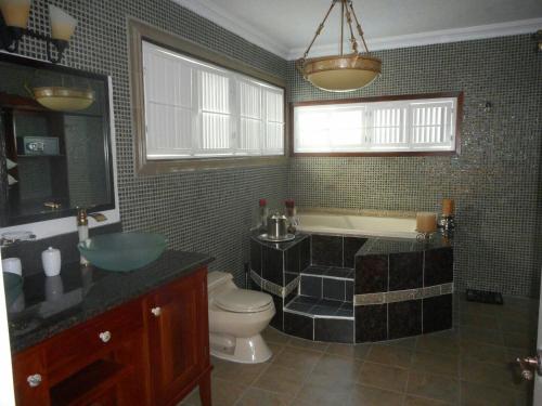 a bathroom with a tub and a toilet and a sink at Royal Vista Villa in Duncans