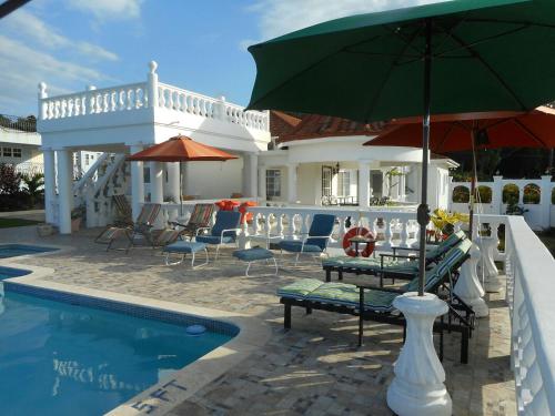 a pool with chairs and an umbrella next to a house at Royal Vista Villa in Duncans