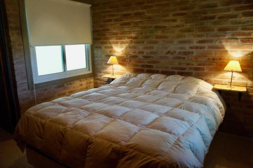 een slaapkamer met een groot bed met een bakstenen muur bij Santa Mate in Nono