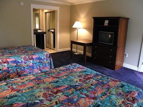 a hotel room with two beds and a television at Magnolia Beach Inn - Fairhope in Fairhope