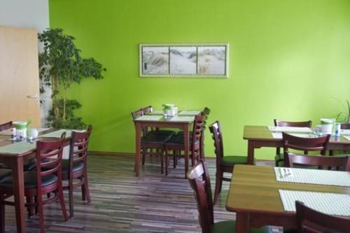 ルートヴィヒスブルクにあるHotel Mörikeの緑の壁と木製のテーブルと椅子が備わるレストラン