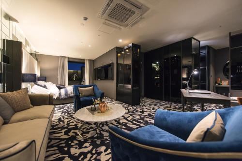 a living room with blue couches and a table at Best Louis Hamilton Hotel Changwon in Changwon