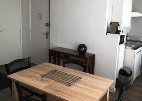 a room with a table and a kitchen with a refrigerator at Résidence et Chambres d'Hôtes de La Porte d'Arras in Douai