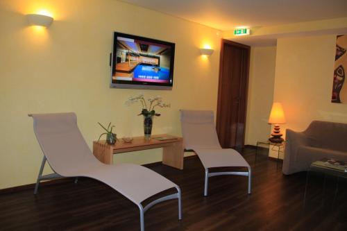 a living room with two chairs and a tv on the wall at Le Bristol Leukerbad in Leukerbad