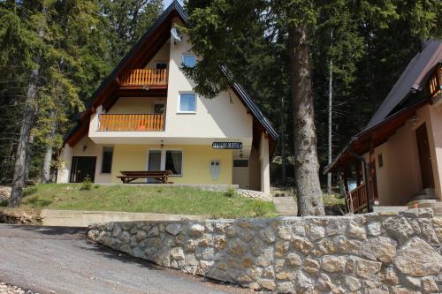 a house with a stone wall in front of it at Vikendica Anja in Vlasic