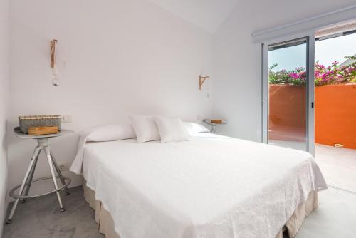 a white bedroom with a bed and a table at Bungalow en Maspalomas, Los Melocotones in Playa del Ingles