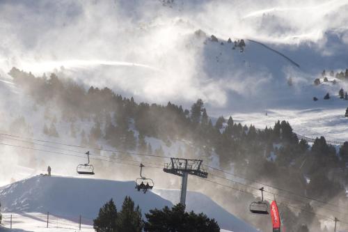 a ski lift with people on it in the snow at Hotel Himàlaia Soldeu by Nexta in Soldeu