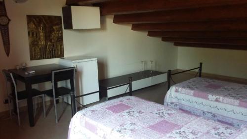 a bedroom with two beds and a table and a desk at B&B Castellazzo in Paceco