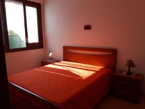 サン・ヴィート・ロ・カーポにあるAppartamenti Giuseppinaのベッドルーム1室(オレンジのシーツが入ったベッド1台、窓付)